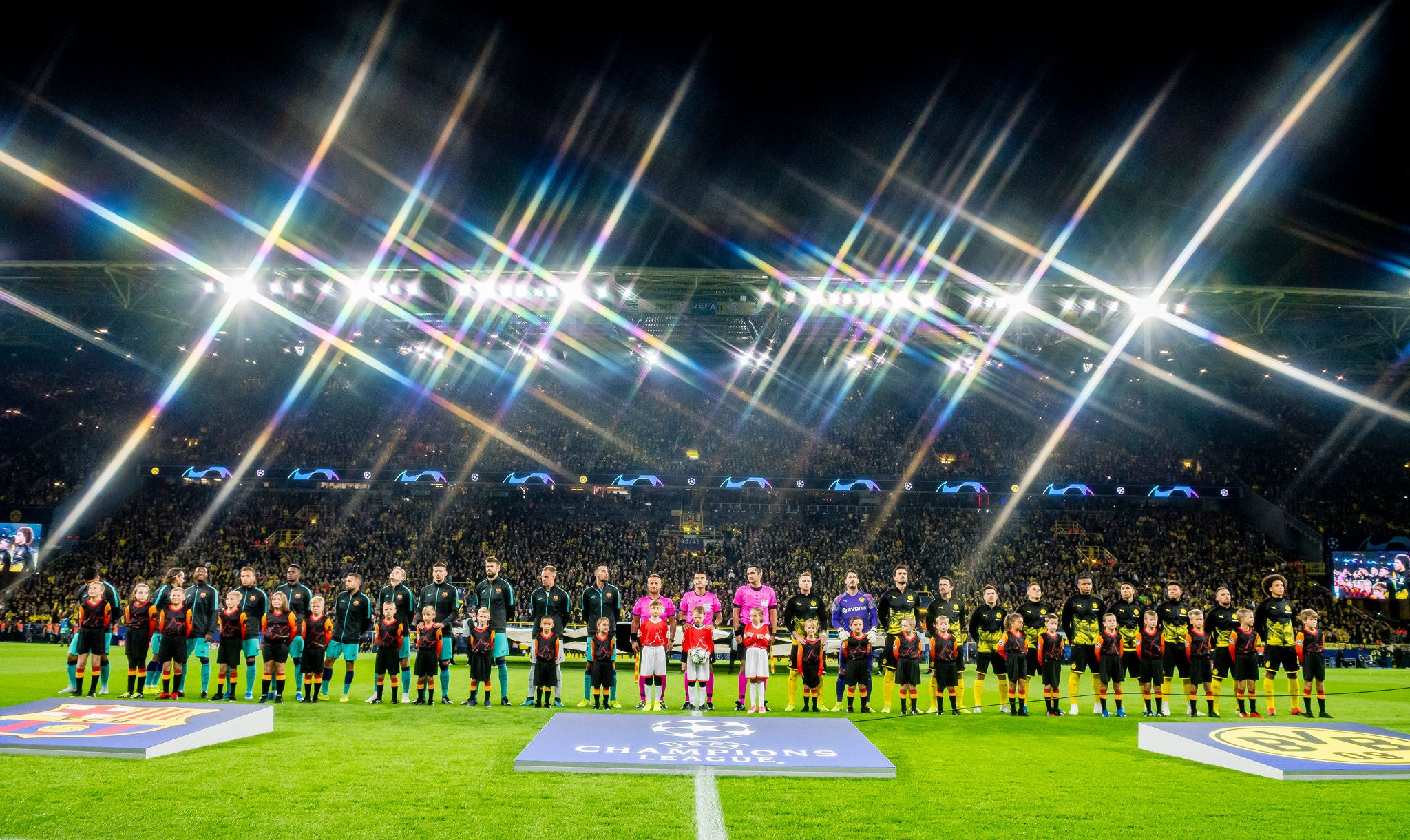 Die Spieler des FC Barcelona, die Schiedsrichter und die Spieler des BVB stehen nebeneinander auf dem Rasen des SIGNAL IDUNA PARK.